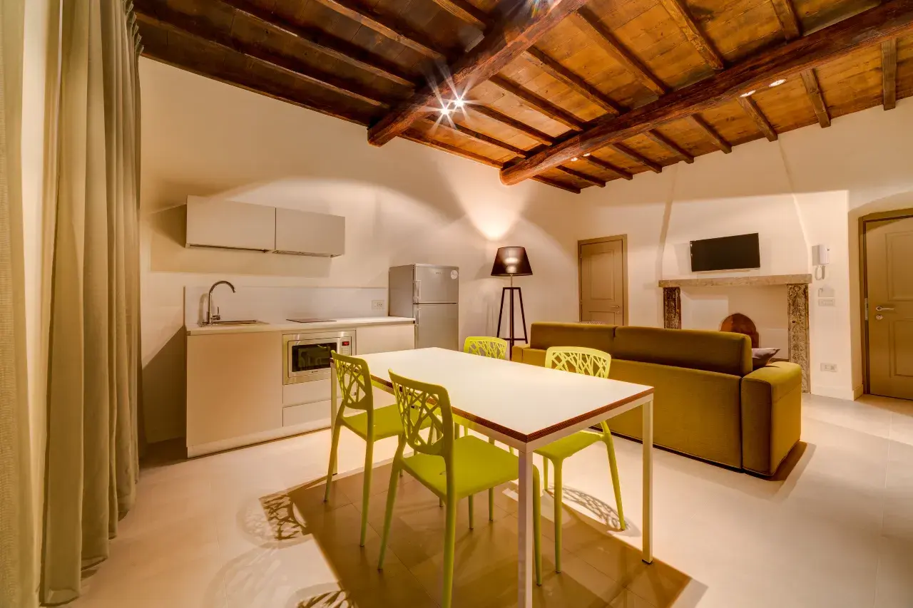Overview of the living area with table, kitchen, and sofa in the Bilo Deluxe apartment at Palazzo Mannaioni, suites in Florence.