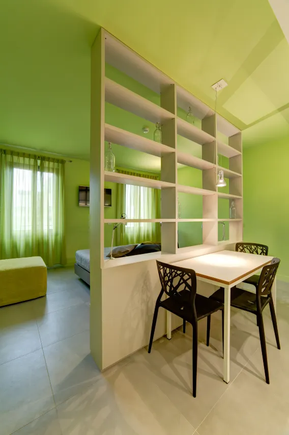 Close-up view of the table and chairs in the Mono Smart apartment with green walls and furnishings.